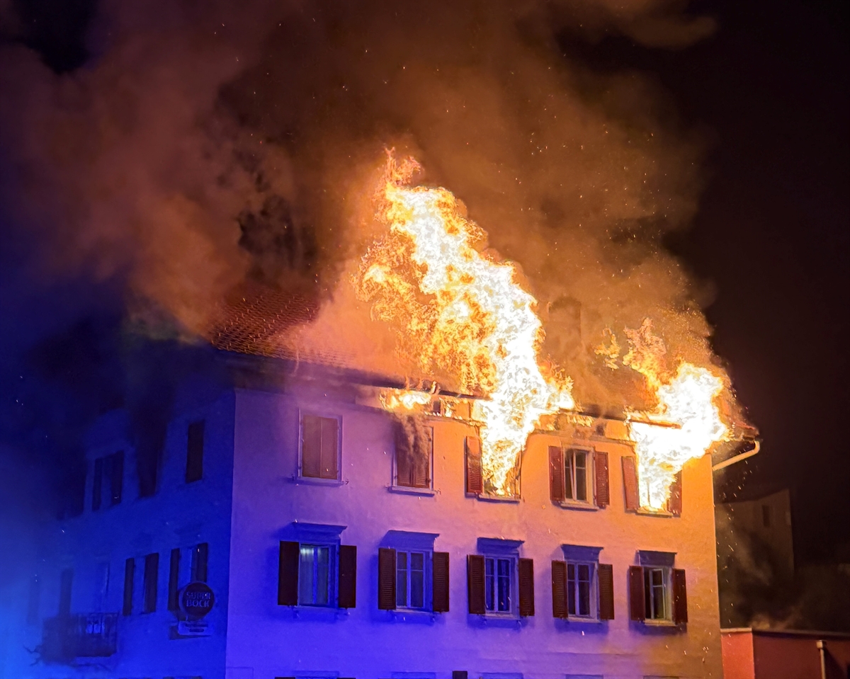 Flammen steigen aus zwei Fenstern in den Nachthimmel