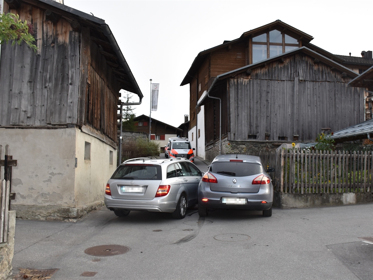 Die beiden nebeneinander verkeilten Unfallautos in der schmalen Gasse von Breil/Brigels. Die Gasse wird von Häusern begrenzt. Dadurch sind die Sichtweiten auf innerhalb der Gassen beschränkt.