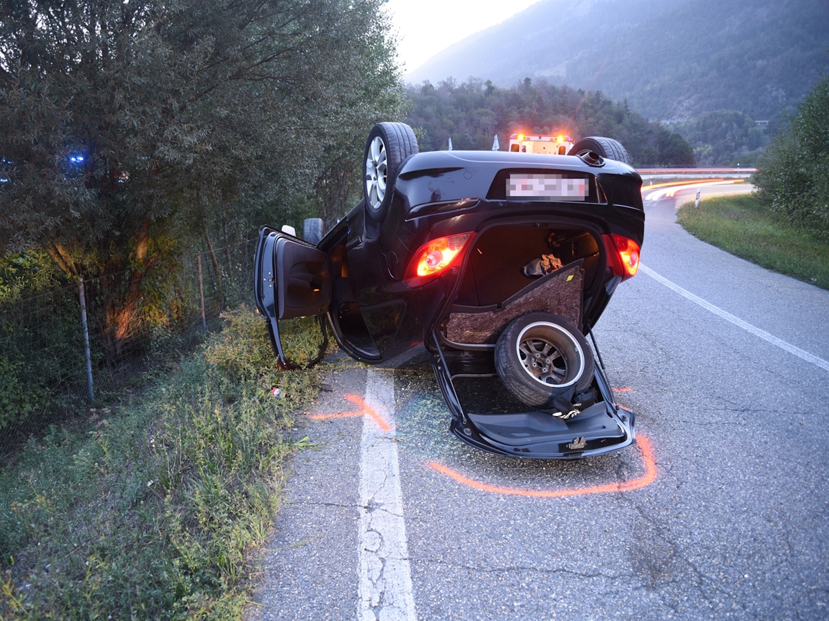 Das Unfallauto liegt auf dem Dach. Im Hintergrund die A13 sowie ein mit gelben Gefahrenlichtern eingeschalteten Rettungswagen.