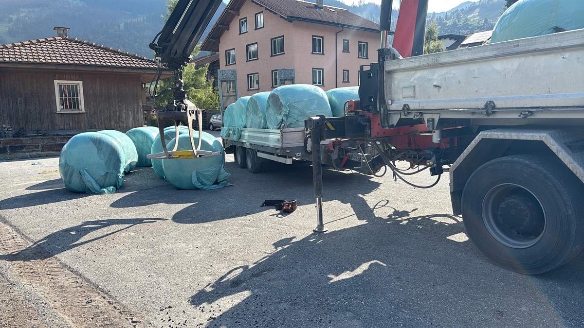 Heuballen in Plastikfolien mit Lastwagenbrücke und Kran