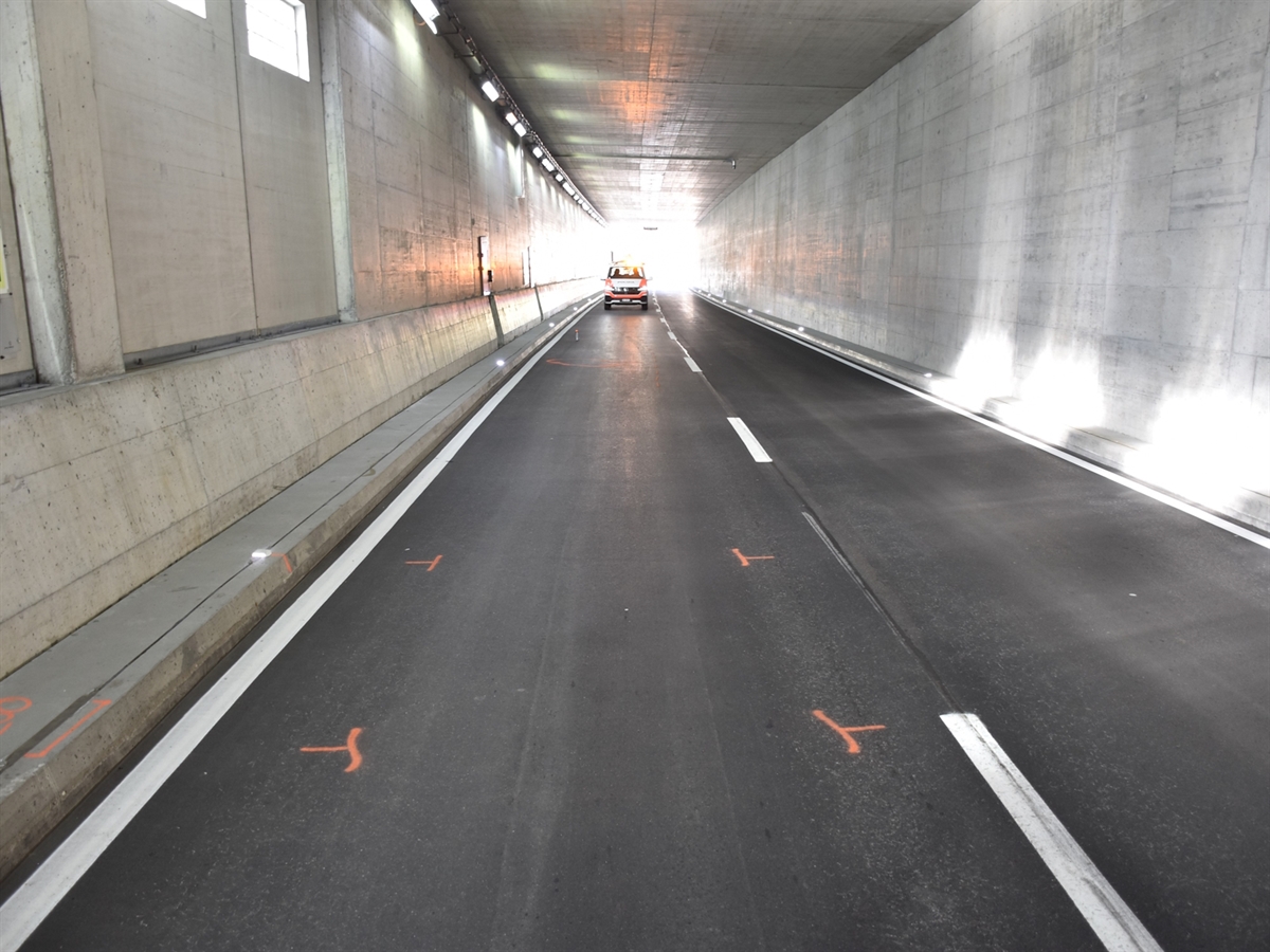 Der Tunnel in Richtung des Eingangs, aus welchem die Fahrzeuge kamen. Am Boden eingezeichnete Unfallspuren. Ein Polizeiauto auf der Strasse.