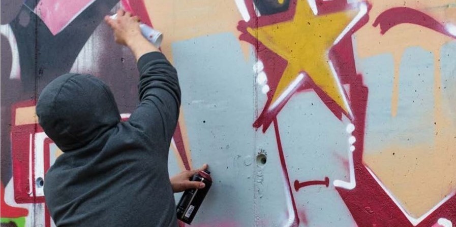 Ein Jugendlicher besprayt eine Wand