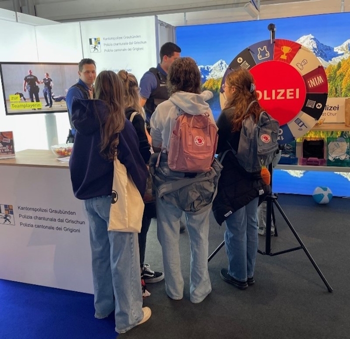 Drei Jugendliche un d zwei Polizisten am Stand der Kantonspolizei Graubünden. 