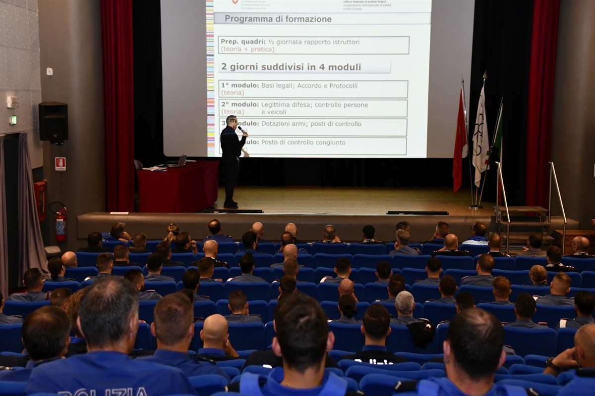 Polizistinnen und Polizisten folgen in einem Saal den Ausführungen eines Referenten auf der Bühne.