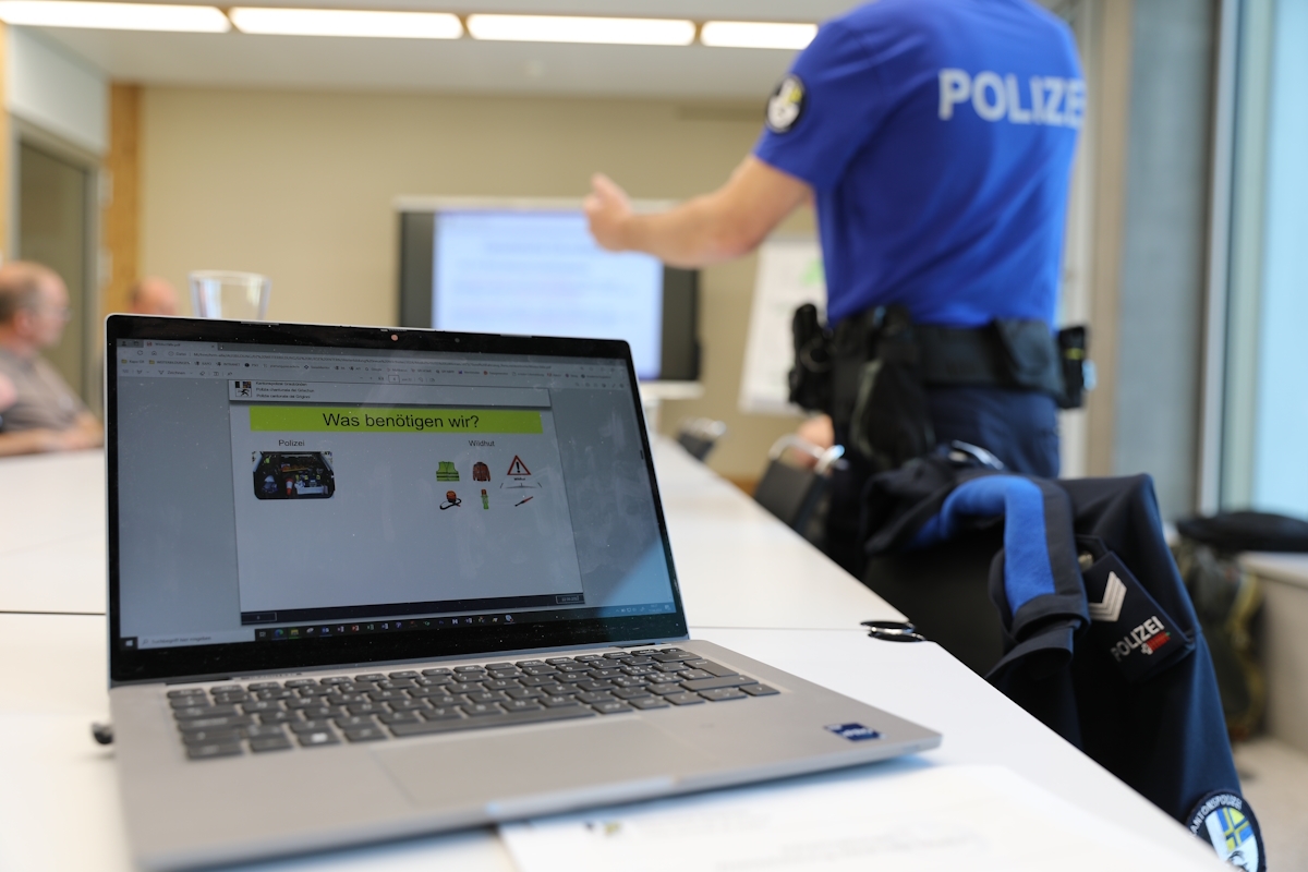 Ein Computer im Vordergrund, dahinter ein Polizist.
