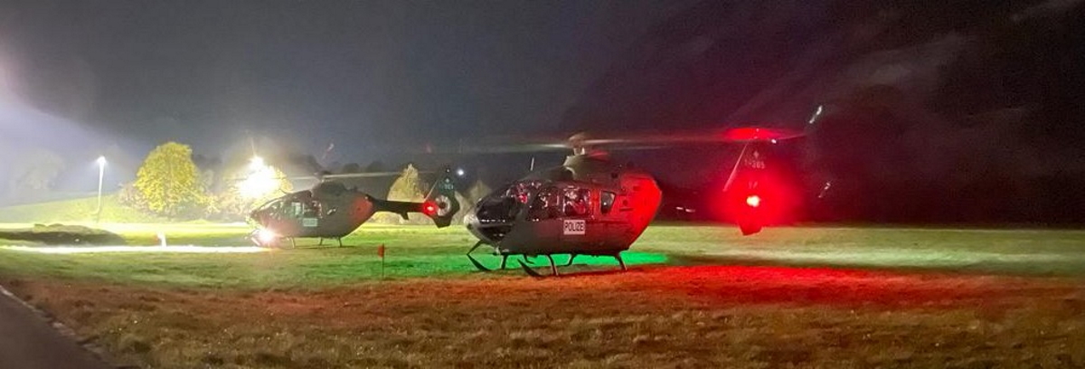 Zwei Helikopter auf dem provisorischen Flugplatz auf dem Rossboden in Chur. Flutlichter beleuchten die Fluggeräte.