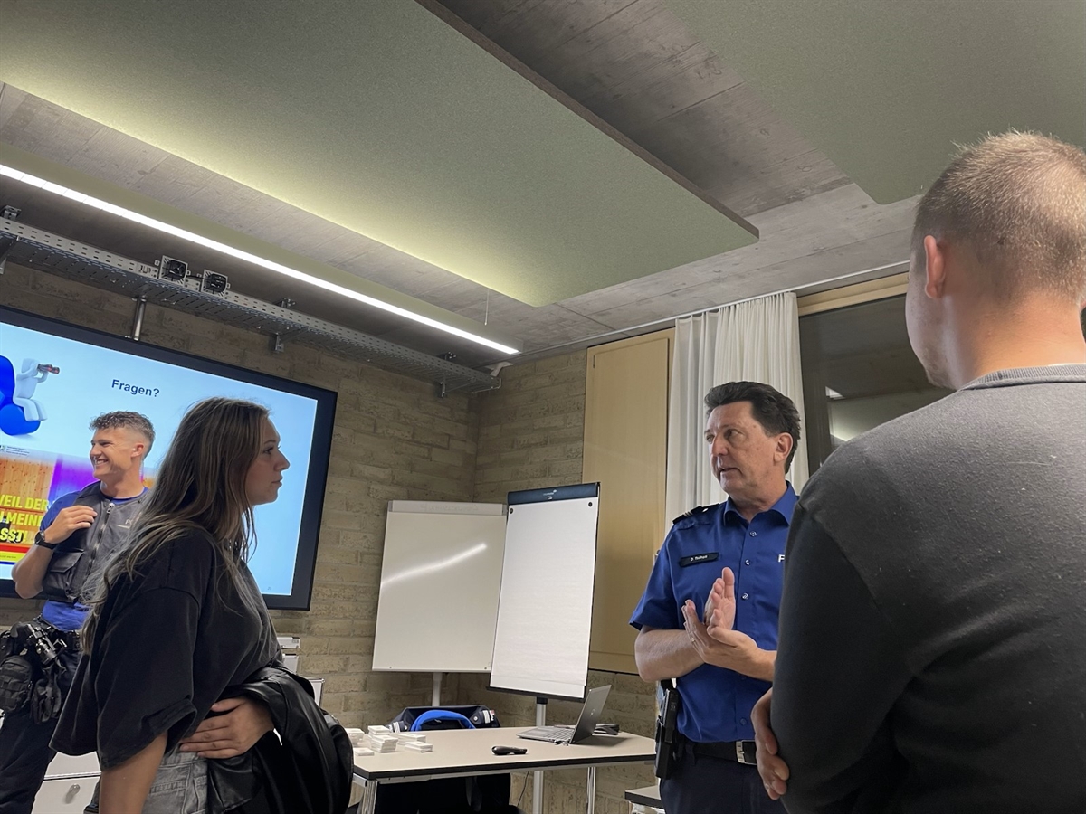 Interessierte im Gespräch mit zwei Polizisten.