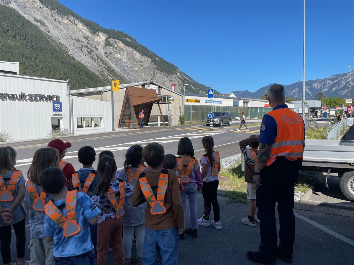 Kinder warten am Strassenrand mit Instruktor