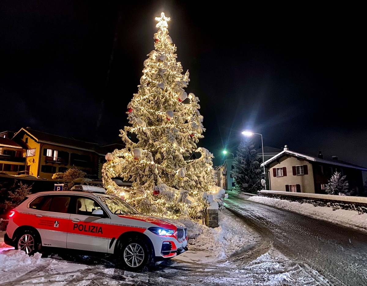 Patrouillenfahrzeug der Kantonspolizei Graubünden vor einem hell erleuchtendem Weihnachtsbaum