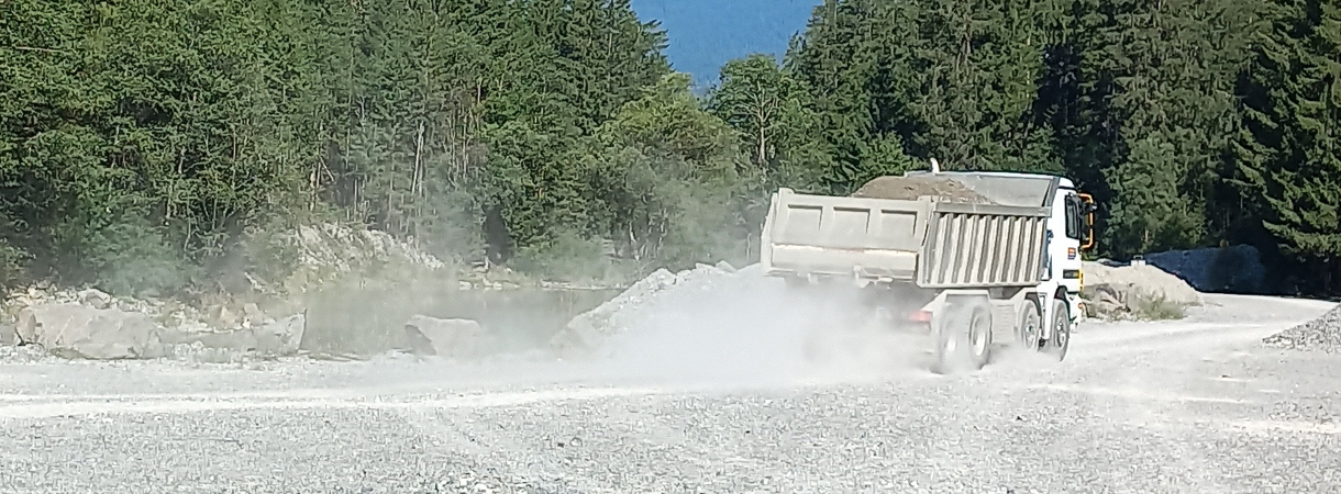 Beladener Lastwagen mit Baumaterial wirbelt Staub auf