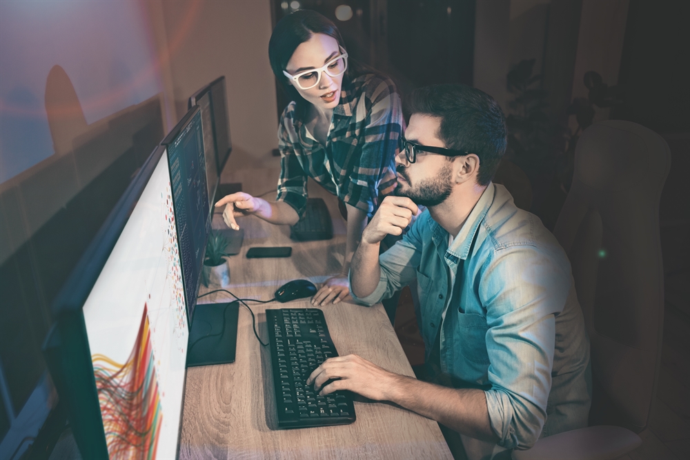 Frau und Mann diskutieren vor Computer, der Daten zeigt