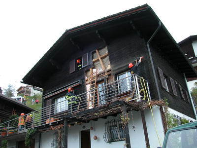 Feuerwehrleute reissen die verbrannte Fassade ab