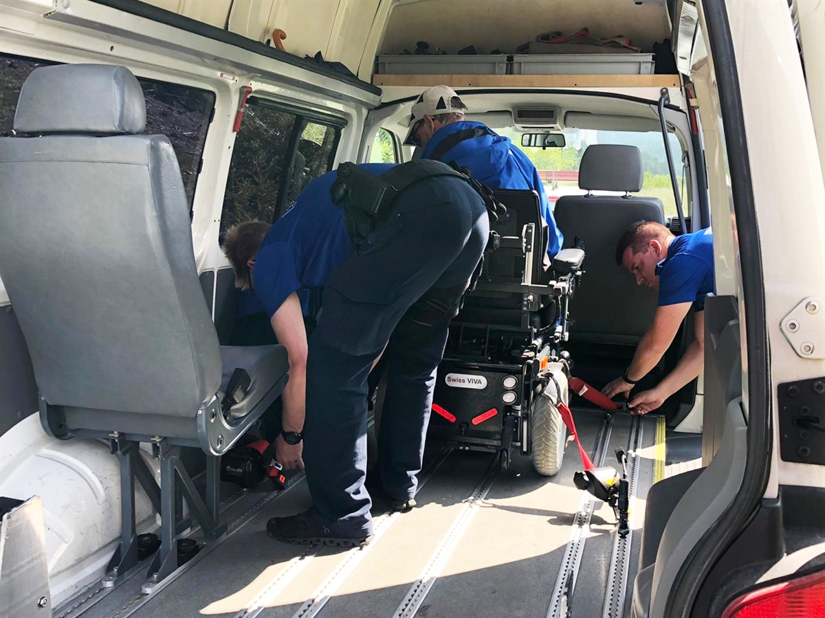 Die Polizisten der Kantonspolizei Graubünden befestigen den Rollstuhlfahrer mit dem Elektrorollstuhl im Rollstuhltransporter.