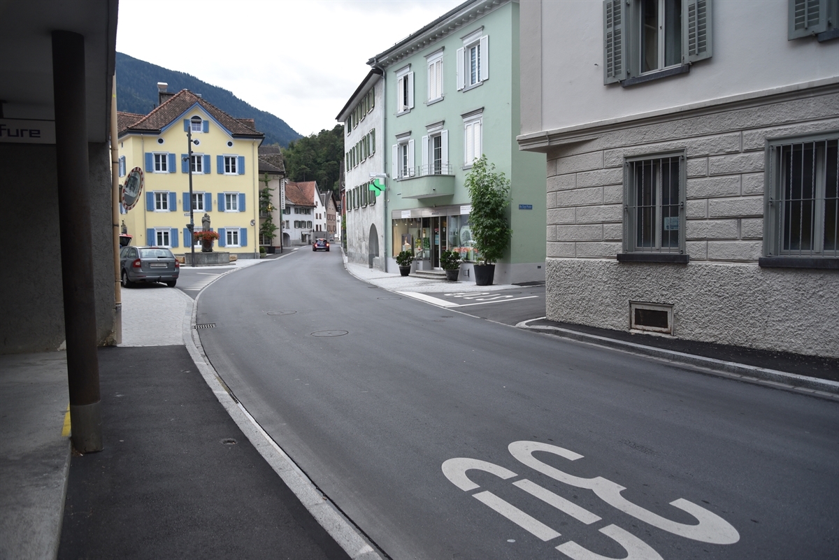 Die Hauptstrasse, links und rechts von Häusern begrenzt. Rechts die in die Hauptstrasse einmündende Via Sogn Pieder und die Bodenmarkierung Stop. An beide Strassen angrenzend ein Vorplatz.