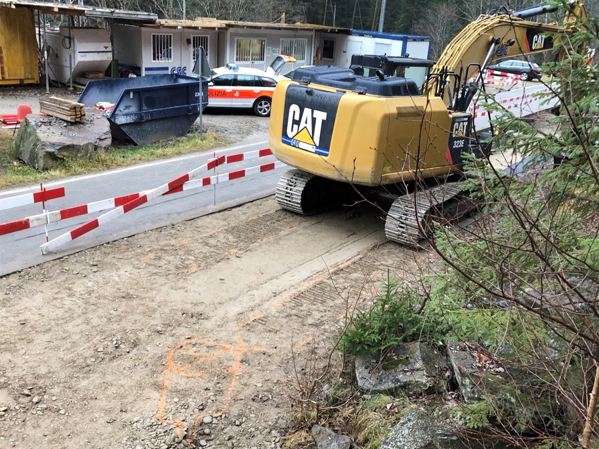 Der Raupenbagger auf der Baustelle. Hinter dem Bagger sind die Spuren der Raupen auf der Schotterstrasse sichtbar. Mit einem Spray wurde die Unfallstelle markiert.