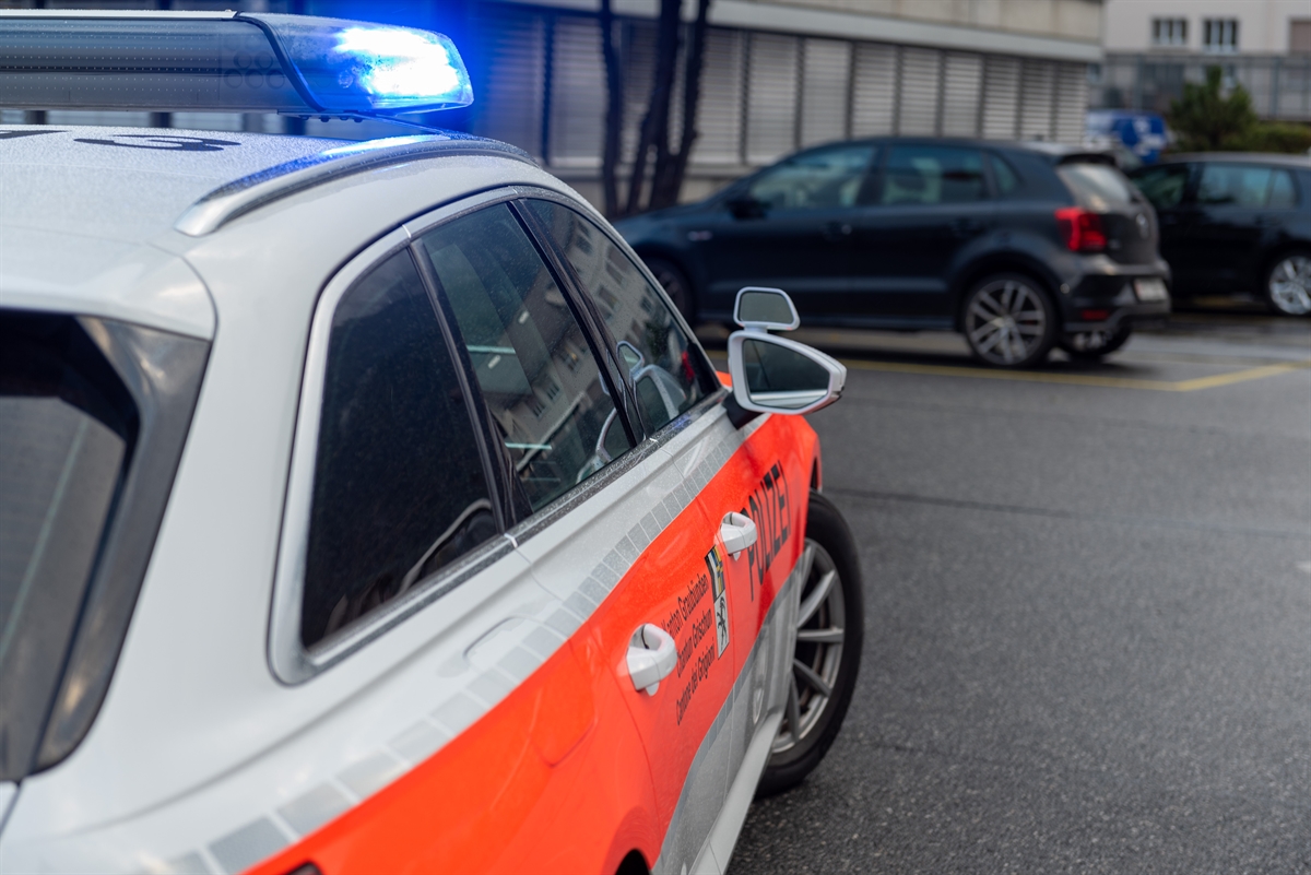 Symbolbild der Kapo Graubünden. Im Vordergrund links ein Patrouillenfahrzeug der Polizei mit eingeschaltetem Blaulicht.