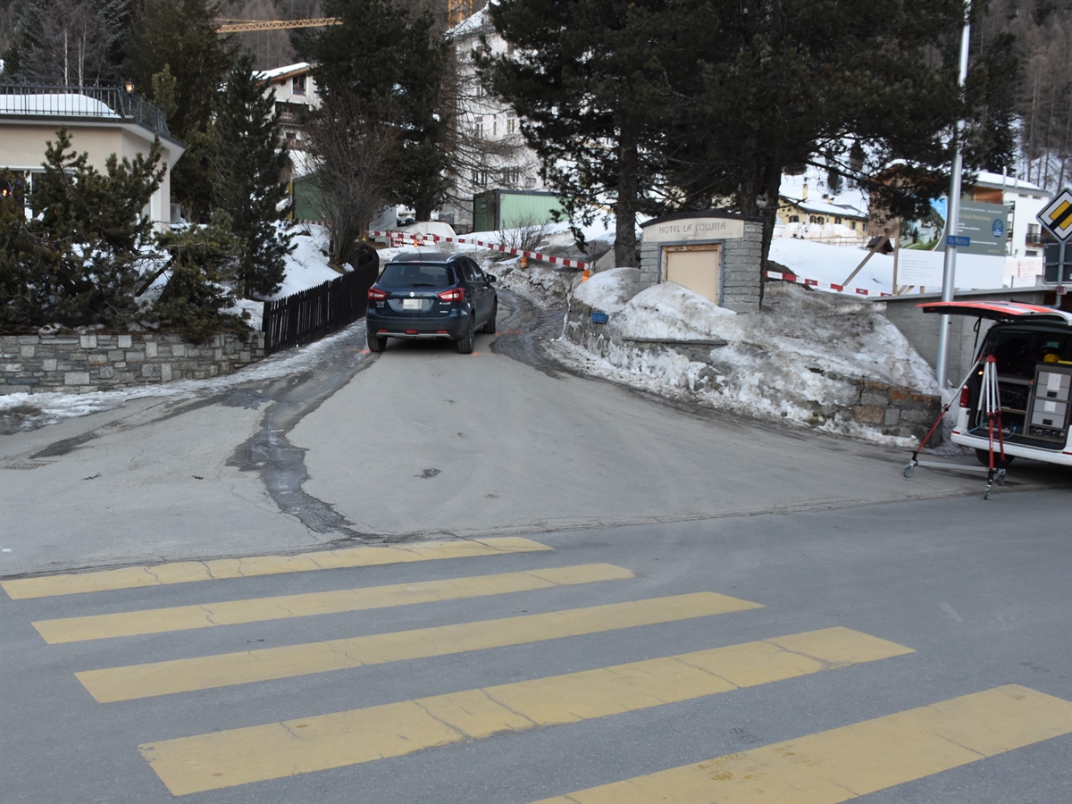 Blick von der Via Maistra in die Via Fullun, in welcher das Unfallauto steht. Rechts auf der Via Maistra ein Polizeiauto mit geöffneter Heckklappe.
