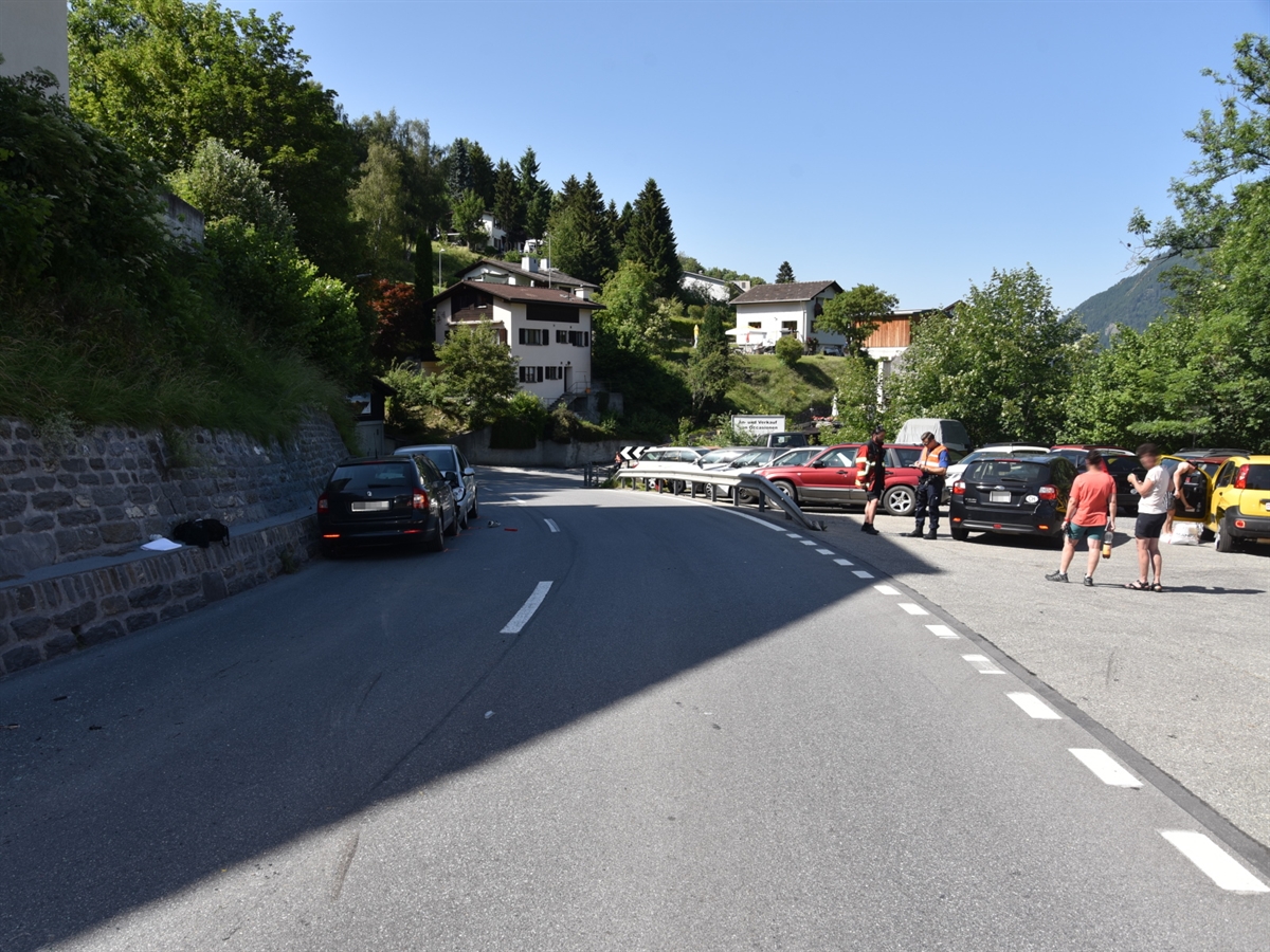 Links die beiden frontal kollidierten Autos. Rechts der Strasse auf einem geteertenPlatz Einsatzkräfte sowie weitere Personen und Fahrzeuge.