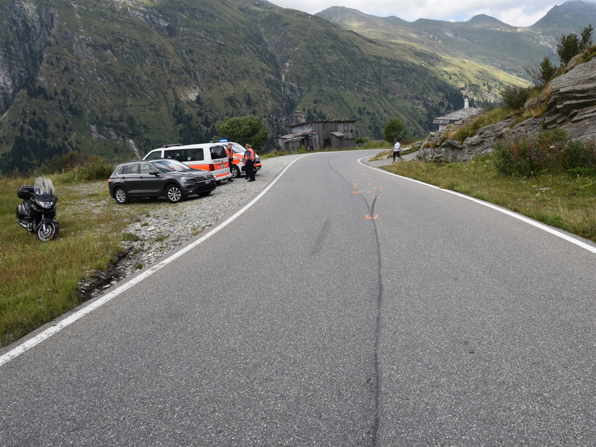 Die San Bernardino Passstrasse mit Bremsspur auf der Fahrbahn. Links im Bild sind zwei Polizeifahrzeuge, ein ziviles Fahrzeug sowie ein Motorrad.
