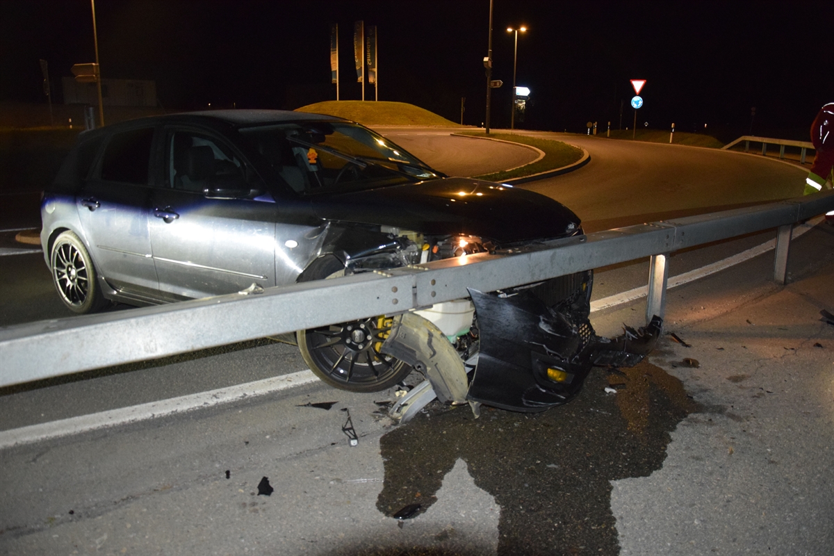 In der Kreiseleinfahrt mit der Leitplanke kollidiertes Auto, vorne rechts defekt, in der Dunkelheit