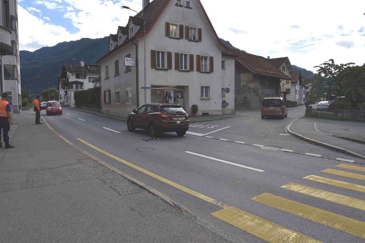 Auf einer Verzweigung steht das Unfallauto und links daneben liegt das Trottinett am Boden. Rechts der Fussgängerstreifen.