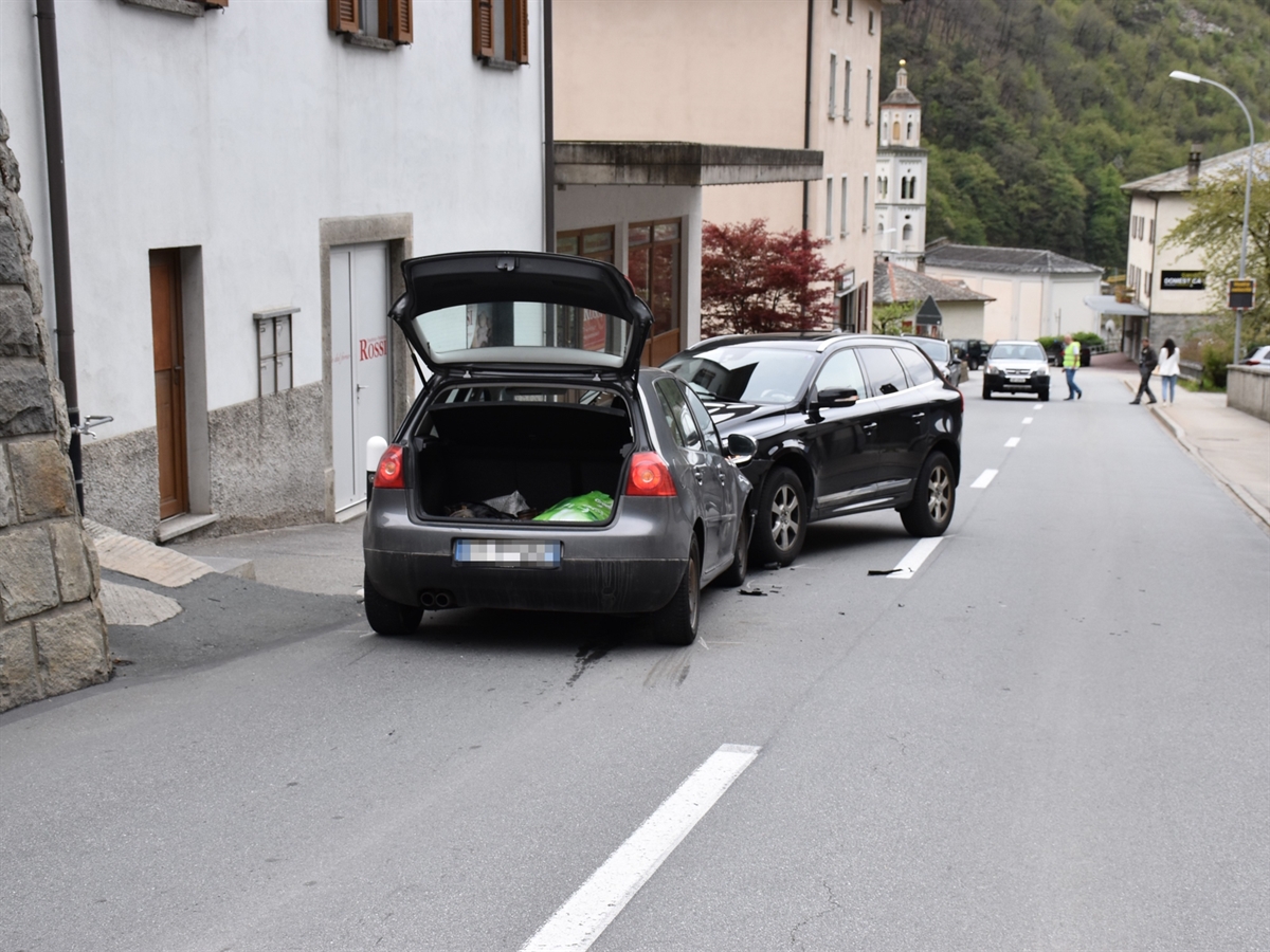 Links der Leitlinie die beiden frontal kollidierten Autos. Links davon Häuser, rechts der Strasse ein Tottoir.