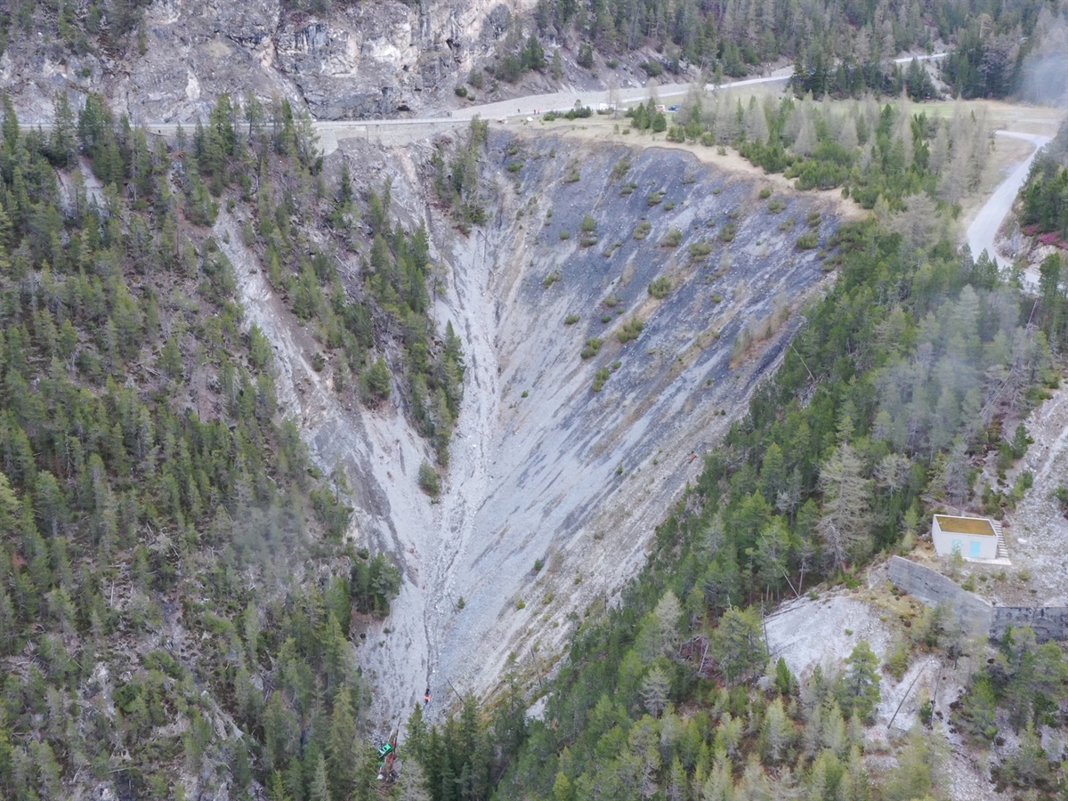 Drohnenbild vom Tobel, in welchem das grüne Fahrzeugwrack liegt.