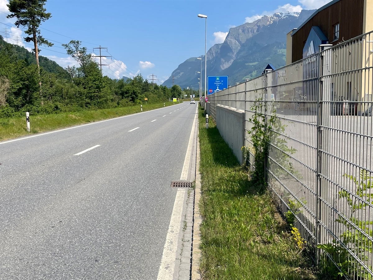 Rechts Gebäude des Designer Outlet. Links anschliessend ein Zaun und links davon die Tardisstrasse. Im Nahbereich ein Abwasserschacht.