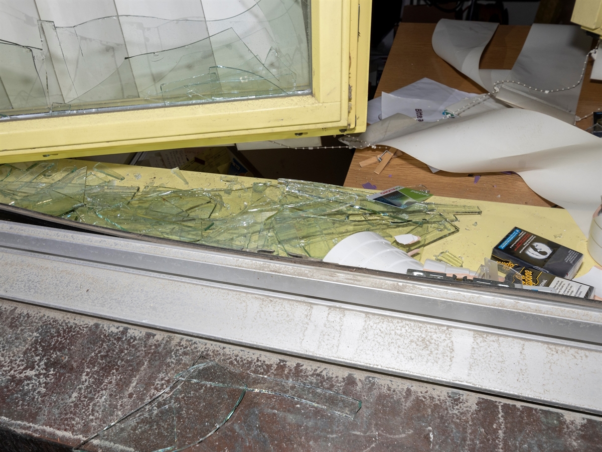 Ein eingeschlagenes Fenster von aussen. Blick in ein Büro.
