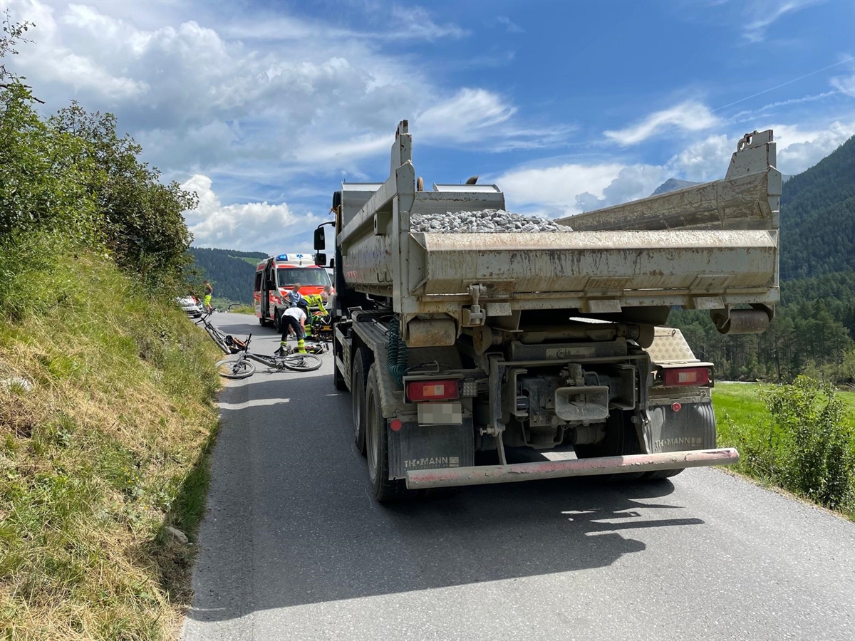 Der Lastwagen von hinten. Vor diesem ein Fahrrad am Boden und sowie Rettungskräfte und eine Ambulanz. Im Hintergrund grösstenteils heiterer Horizont.