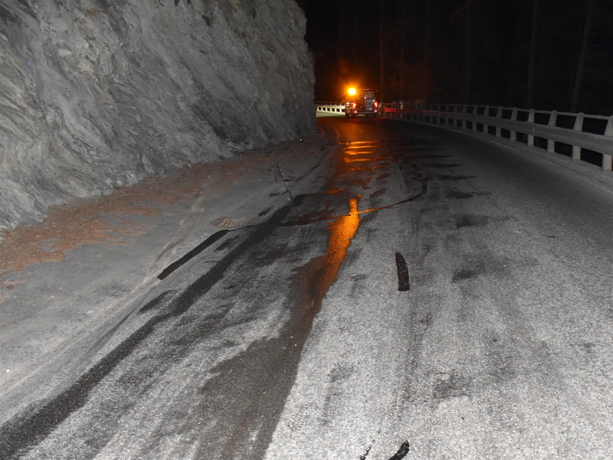 Nächtliche Aufnahme der Unfallstelle. Links die Felswand und in der oberen Bildmitte ein Polizeiauto. Auf der Fahrbahn sind Brems-, Schleuder- und Kratzspuren ersichtlich.