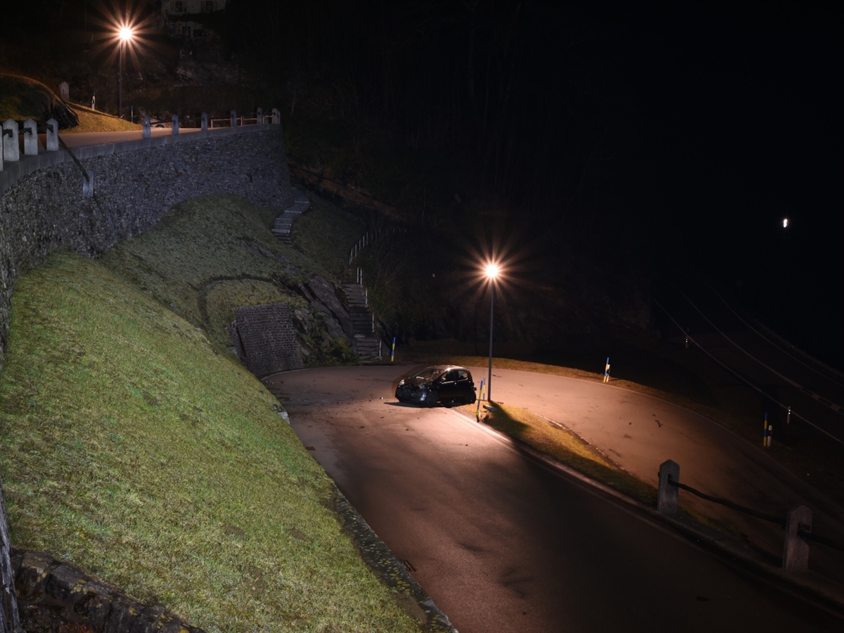 Links der höher gelegene Strassenabschnitt mit dem durchbrochenen Zaun. Rechts davon die steil abfallende Böschung und das Auto auf dem rund 10 Meter tiefer gelegenen Strassenabschnitt.