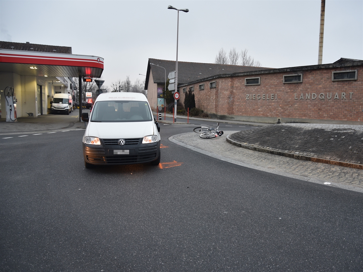 Mit Sicht in Richtung Malans steht das Auto mitten auf der Fahrspur im Kreisel. Rechts davon liegt das Velo bei der Kreiselmitte. Im Hintergrund eine Tankstelle sowie das Gebäude der Ziegelei Landquart.