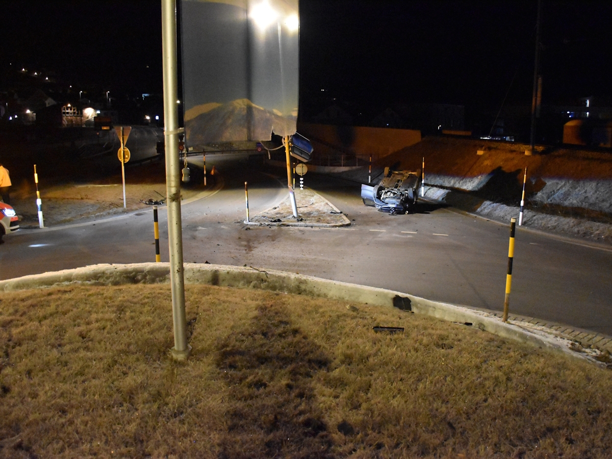 Nachtaufnahme mit Blick vom Kreiselhügel auf den Kreiselausgang in welchem das Unfallauto auf dem Dach liegt. In Bildmitte der beschädigte Kandelaber.