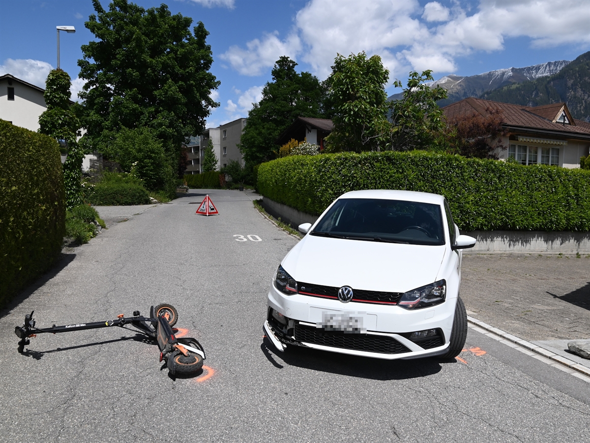 Das weisse Unfallauto steht mit Front auf dem Caznerweg. Das E-Trottinett liegt links neben der Front. Im Hintergrund ein Polizeisignal auf der Fahrbahn.