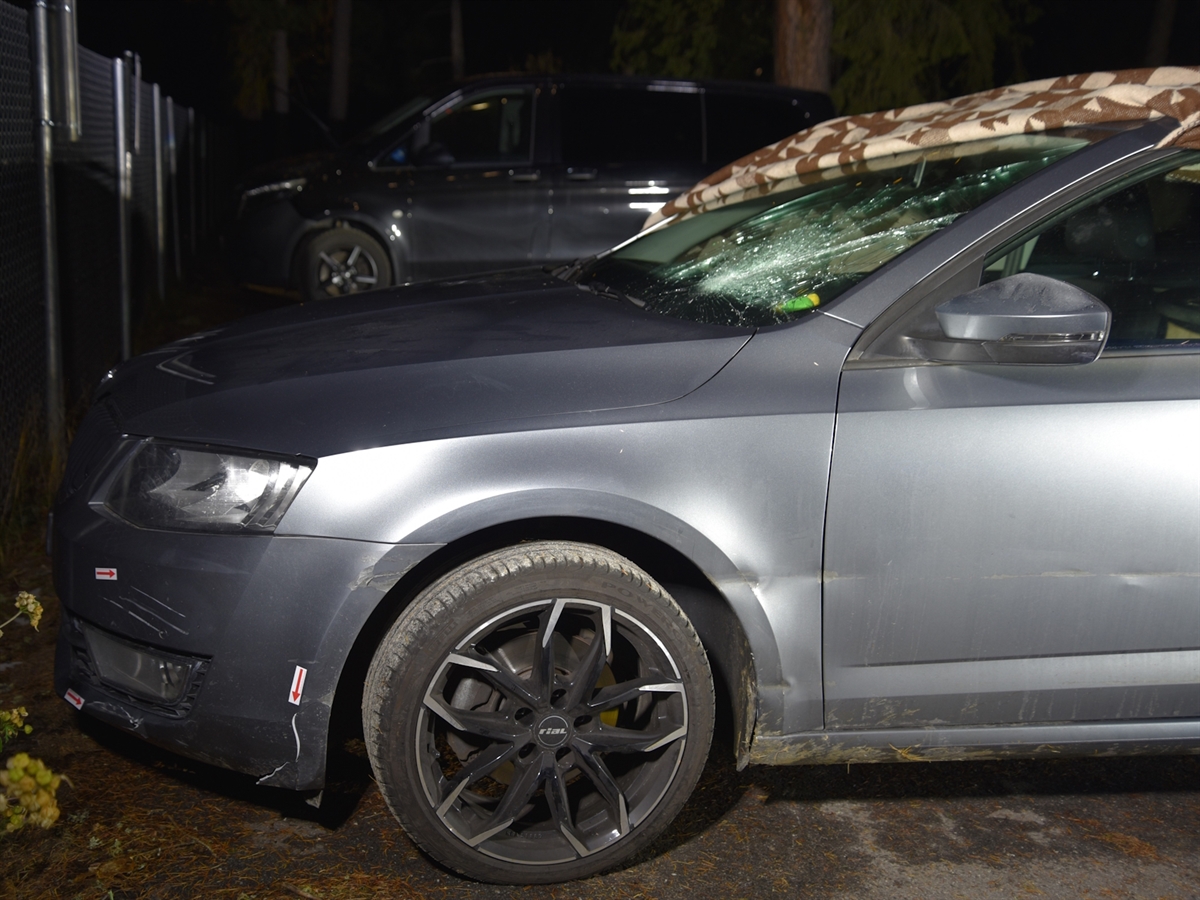 Das mit einer Decke auf der Frontscheibe abgedeckte Unfallfahrzeug auf einem Parkplatz. Die Frontscheibe sowie die linke Seite der Fahrzeugfront weist diverse Schäden auf.
