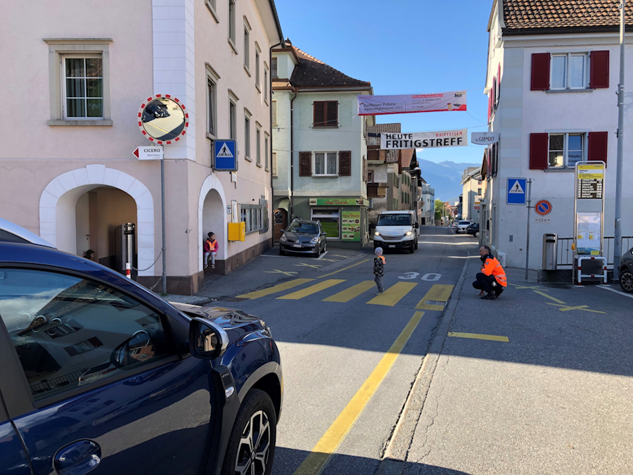 Ein Polizist instruiert ein Kindergärtner wie er in Zizers beim Rathaus über den Fussgängerstreifen laufen muss