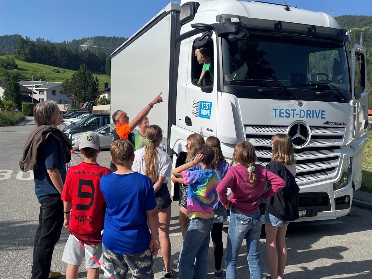 Guardando allo specchietto laterale, l'istruttore del traffico spiega ai bambini i diversi problemi dell'angolo morto